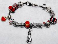 Kitty Bracelet 1 is designed from the Pugdora line -  snake chain measuring 7.50" (19.05 cm) and features large-holed Lampwork beads in reds with metal Bali beads including a kitty-themed bead, and kitty and heart charms. Clasp easily snaps open and closed.
